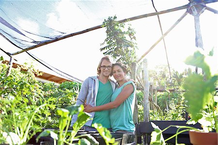 Portrait of smiling couple embracing in greenhouse, seedlings in foreground Stock Photo - Premium Royalty-Free, Code: 6113-07808404
