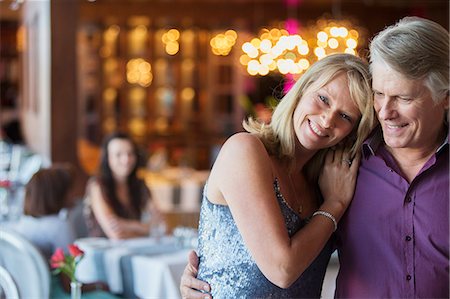 simsearch:6113-07992186,k - Man embracing woman in restaurant, people in background Stock Photo - Premium Royalty-Free, Code: 6113-07808555