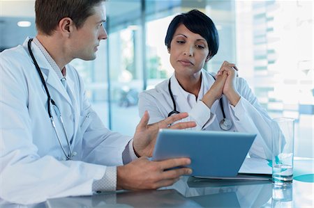 simsearch:6108-06907153,k - Doctors discussing patient's treatment at desk, using digital tablet Stock Photo - Premium Royalty-Free, Code: 6113-07808685