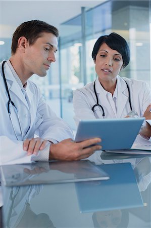 simsearch:6108-06907153,k - Doctors discussing patient's treatment at desk, using digital tablet Stock Photo - Premium Royalty-Free, Code: 6113-07808701