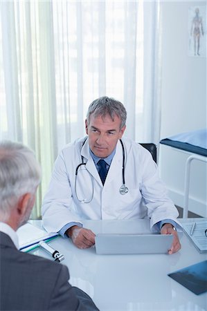 simsearch:6108-06907153,k - Mature doctor with laptop and man sitting at desk in office Stock Photo - Premium Royalty-Free, Code: 6113-07808707