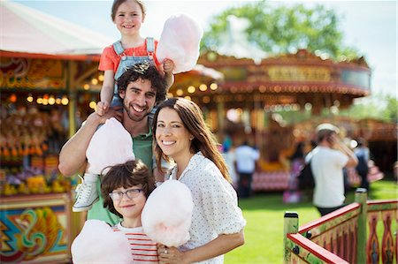 Portrait of cheerful family holding pink candy floss in amusement park Stock Photo - Premium Royalty-Free, Code: 6113-07961538