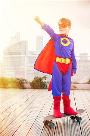 excited child - Superhero boy standing on skateboard on city rooftop Photographie de stock - Premium Libres de Droits, Code: 6113-07961717