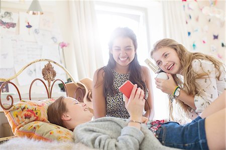 Three teenage girls listening to music from smartphone in bedroom Stock Photo - Premium Royalty-Free, Code: 6113-07991985