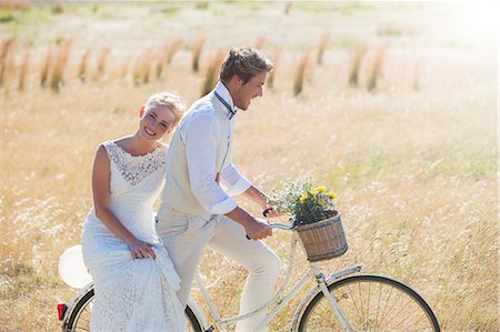 Young couple riding bike in meadow Stock Photo - Premium Royalty-Free, Code: 6113-07992156