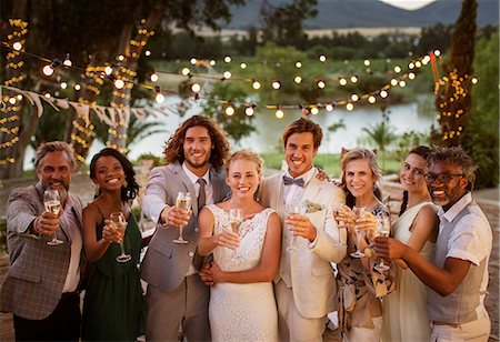 Portrait of young couple with guests toasting with champagne during wedding reception at dusk Stock Photo - Premium Royalty-Free, Code: 6113-07992197