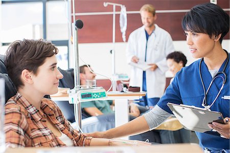 Female doctor holding clip board checking with female patient in outpatient clinic Foto de stock - Sin royalties Premium, Código: 6113-07905952