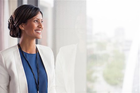 simsearch:6108-06907153,k - Portrait of smiling mid adult woman looking through window Stock Photo - Premium Royalty-Free, Code: 6113-07906095
