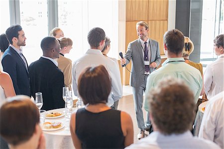 speaker - Portrait of smiling man standing in conference room, offering microphone to person in audience Stock Photo - Premium Royalty-Free, Code: 6113-07906110