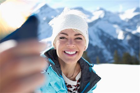 Smiling woman taking selfie in snow Stock Photo - Premium Royalty-Free, Code: 6113-07906620