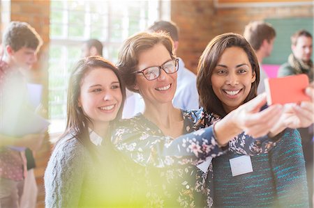 Women taking selfie with camera phone in community center Stock Photo - Premium Royalty-Free, Code: 6113-08087974