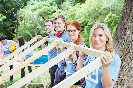 Portrait of smiling volunteers lifting construction frame Stock Photo - Premium Royalty-Free, Code: 6113-08088016