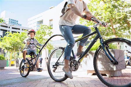 simsearch:6113-08171298,k - Son in helmet riding tandem bicycle with mother in urban park Photographie de stock - Premium Libres de Droits, Code: 6113-08171357