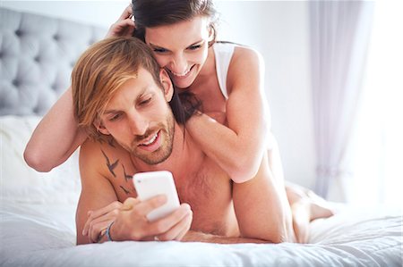 simsearch:6108-05873097,k - Couple laying on bed texting with cell phone Stock Photo - Premium Royalty-Free, Code: 6113-08171389