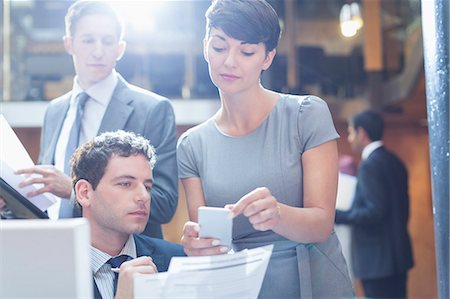 Business people looking at cell phone in office Stock Photo - Premium Royalty-Free, Code: 6113-08184274