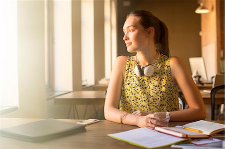 day calendar with plans - Pensive casual businesswoman with headphones looking away in office Stock Photo - Premium Royalty-Free, Code: 6113-08105371