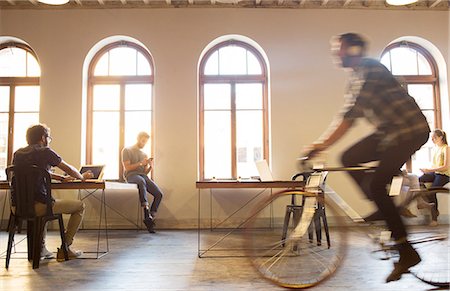 Casual businessman riding bicycle in open office Stock Photo - Premium Royalty-Free, Code: 6113-08105412