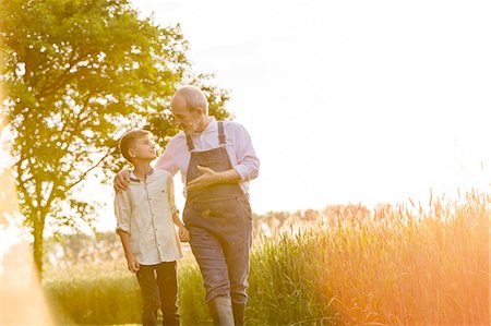 senior lens flare - Grandfather farmer talking to grandson in sunny rural wheat field Stock Photo - Premium Royalty-Free, Code: 6113-08220484