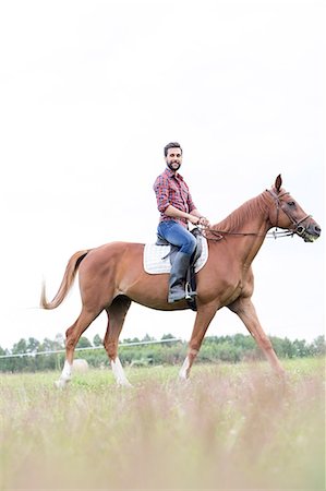 Portrait smiling man horseback riding in rural field Photographie de stock - Premium Libres de Droits, Code: 6113-08220425