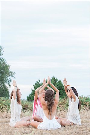 prayer position - Boho women meditating with hands clasped overhead in circle in rural field Stock Photo - Premium Royalty-Free, Code: 6113-08220549