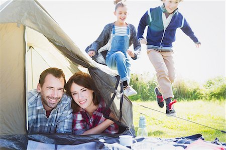 simsearch:6113-07242296,k - Portrait smiling couple in tent with kids playing nearby Stock Photo - Premium Royalty-Free, Code: 6113-08393797