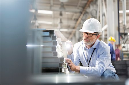 Engineer examining steel parts with flashlight in factory Stock Photo - Premium Royalty-Free, Code: 6113-08393854