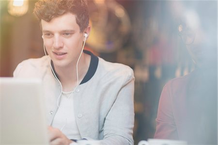 Man listening to music on headphones and using laptop Stock Photo - Premium Royalty-Free, Code: 6113-08321081