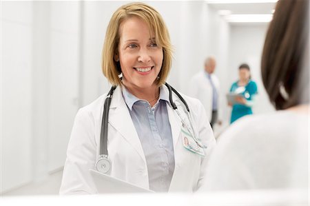 Smiling doctor talking to patient in hospital corridor Stock Photo - Premium Royalty-Free, Code: 6113-08321295