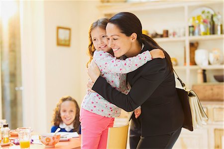 Working mother hugging daughter goodbye at breakfast table Stock Photo - Premium Royalty-Free, Code: 6113-08321558