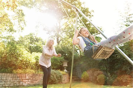 swing - Grandmother pushing granddaughter on swing in backyard Stock Photo - Premium Royalty-Free, Code: 6113-08321610