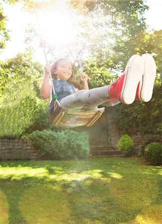 Enthusiastic girl swinging in sunny backyard Stock Photo - Premium Royalty-Free, Code: 6113-08321616