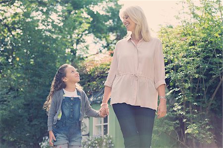 Grandmother and granddaughter holding hands and walking in garden Stock Photo - Premium Royalty-Free, Code: 6113-08321631