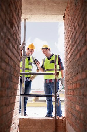 Construction workers texting with cell phone at construction site Stock Photo - Premium Royalty-Free, Code: 6113-08321756