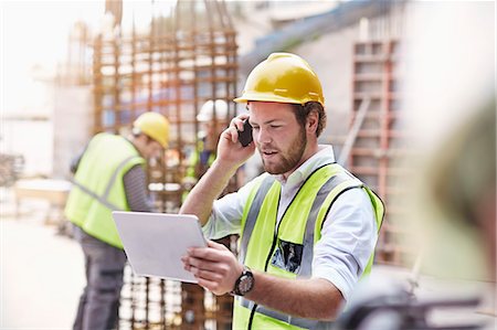 Engineer with digital tablet talking on cell phone at construction site Stock Photo - Premium Royalty-Free, Code: 6113-08321770