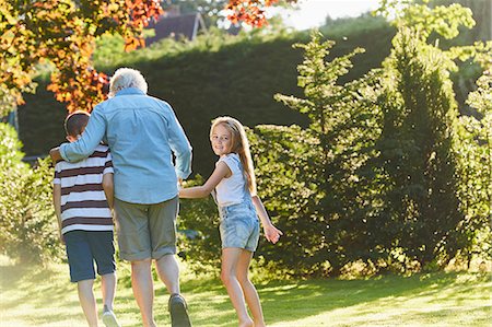 Portrait smiling girl walking with grandmother and brother in garden Stock Photo - Premium Royalty-Free, Code: 6113-08424188
