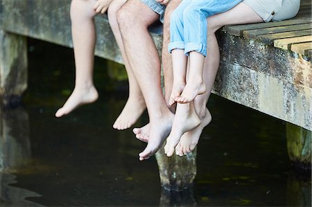 simsearch:649-07803505,k - Family dangling bare feet over dock Stock Photo - Premium Royalty-Free, Code: 6113-08424193