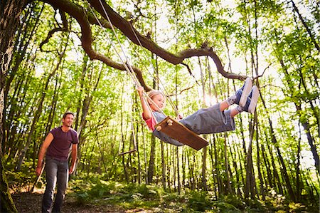 swings - Father pushing daughter on rope swing in forest Stock Photo - Premium Royalty-Free, Code: 6113-08424268