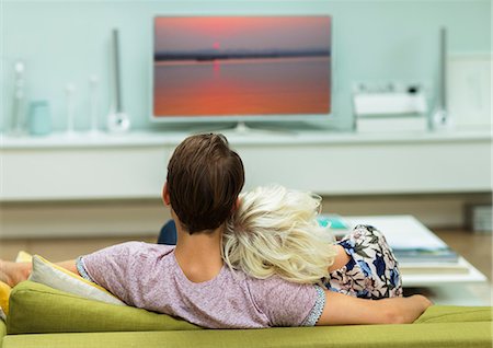 simsearch:6113-07790495,k - Relaxed couple watching TV on living room sofa Stock Photo - Premium Royalty-Free, Code: 6113-08550051