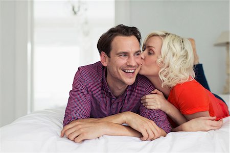 simsearch:6113-06720867,k - Affectionate wife kissing smiling husband on bed Stock Photo - Premium Royalty-Free, Code: 6113-08550061