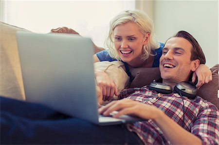 Smiling couple using laptop on living room sofa Stock Photo - Premium Royalty-Free, Code: 6113-08550091