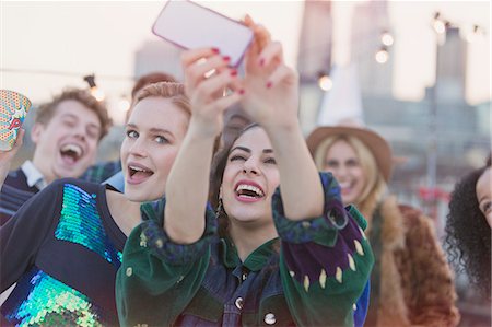 simsearch:6113-07648679,k - Young women laughing and taking selfie at rooftop party Stock Photo - Premium Royalty-Free, Code: 6113-08568589