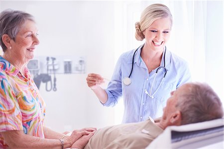 Smiling doctor checking senior man's temperature Stock Photo - Premium Royalty-Free, Code: 6113-08568751