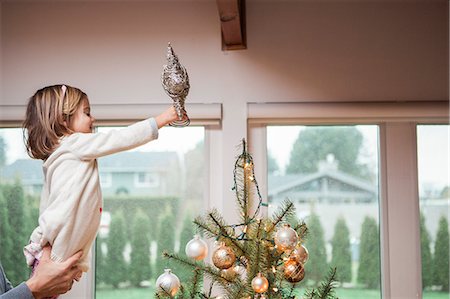 family at christmas - Toddler girl putting star on Christmas tree Foto de stock - Sin royalties Premium, Código: 6113-08521295