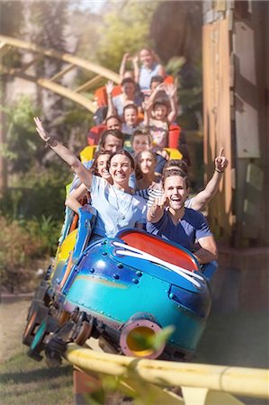 people riding roller coasters - Portrait enthusiastic friends cheering and riding roller coaster at amusement park Foto de stock - Sin royalties Premium, Código: 6113-08521349
