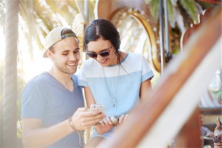 simsearch:6108-05873097,k - Young couple texting with cell phone at amusement park Stock Photo - Premium Royalty-Free, Code: 6113-08521338