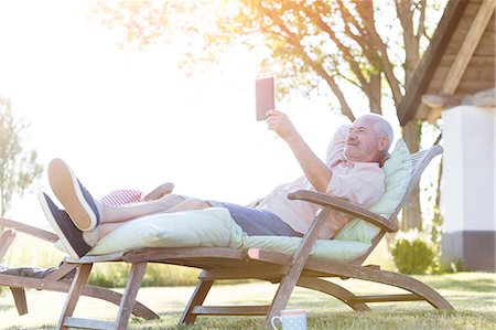 Senior man using digital tablet relaxing on lounge chair in backyard Stock Photo - Premium Royalty-Free, Code: 6113-08521540
