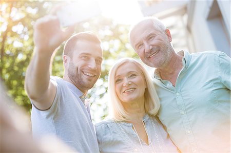 simsearch:6113-06498180,k - Smiling senior couple and adult son taking selfie outdoors Stock Photo - Premium Royalty-Free, Code: 6113-08521510