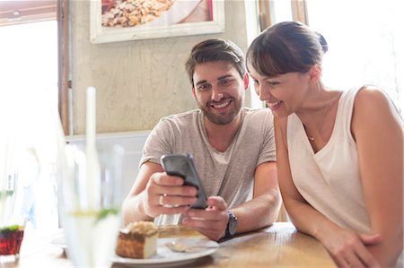 simsearch:6113-06899638,k - Couple texting with cell phone at cafe table Stock Photo - Premium Royalty-Free, Code: 6113-08521620