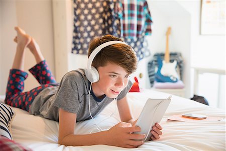 Boy with headphones listening to music on digital tablet Stock Photo - Premium Royalty-Free, Code: 6113-08655371