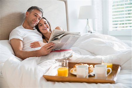 simsearch:6113-07543549,k - Smiling couple reading newspaper enjoying breakfast in bed Stock Photo - Premium Royalty-Free, Code: 6113-08655457